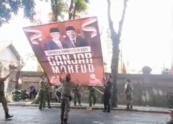 Petugas Satpol PP Bali saat menurunkan baliho bergambar Ganjar-Mahfud di di Desa Batu Bulan, Kabupaten Gianyar, Bali/Sumber Foto: Kompas.com
